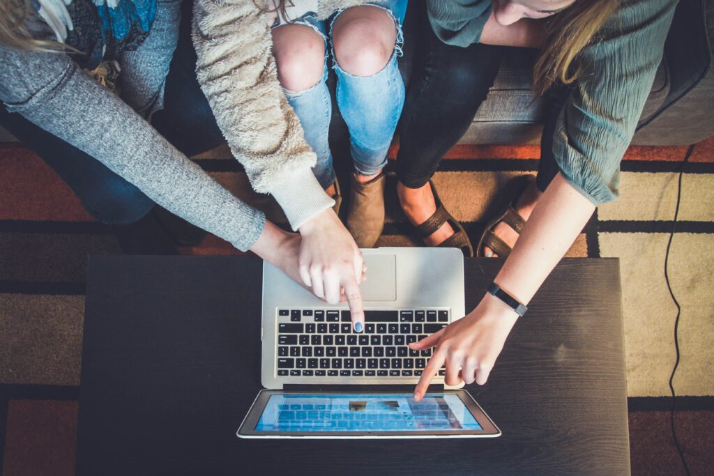 Photo of three girls pointing at a laptop and working collaboratively
