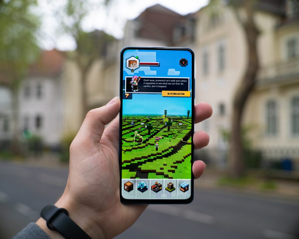 Image of a person holding a phone with Minecraft playing on the screen